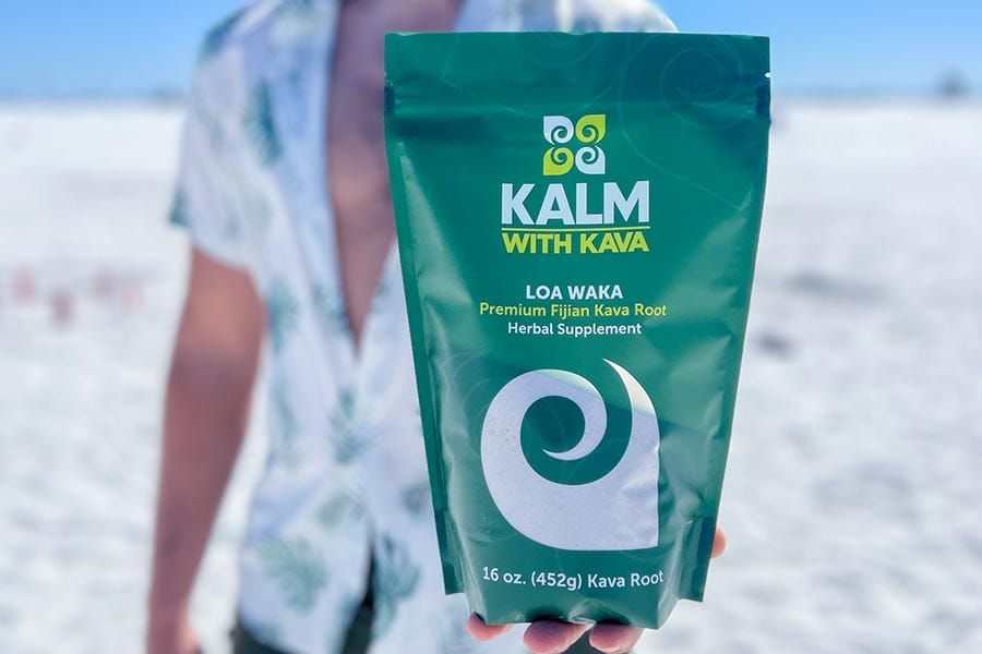 Man holding a bag of Kava from Kalm with Kava on the beach