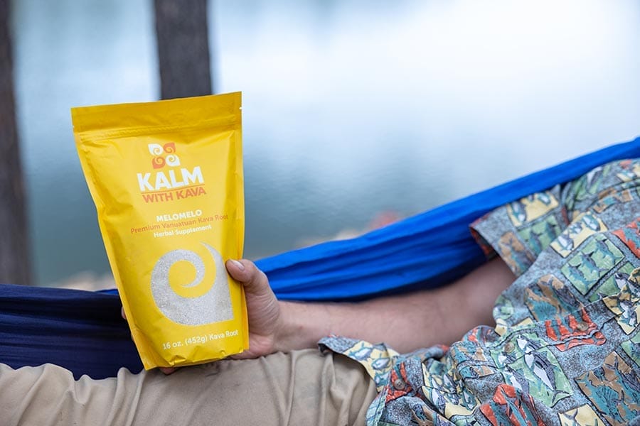 Man in a hammock holding a bag of Melomelo kava