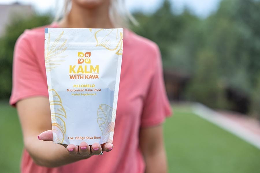 Woman holding a bag of Melomelo Micronized Kava from Kalm with Kava